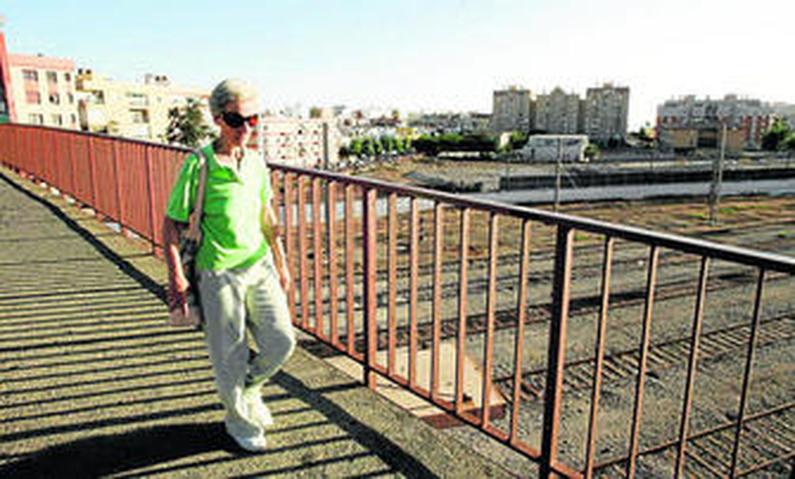 Una mujer cruza la pasarela de la estación sin el viejo silo del mineral en el paisaje urbano.