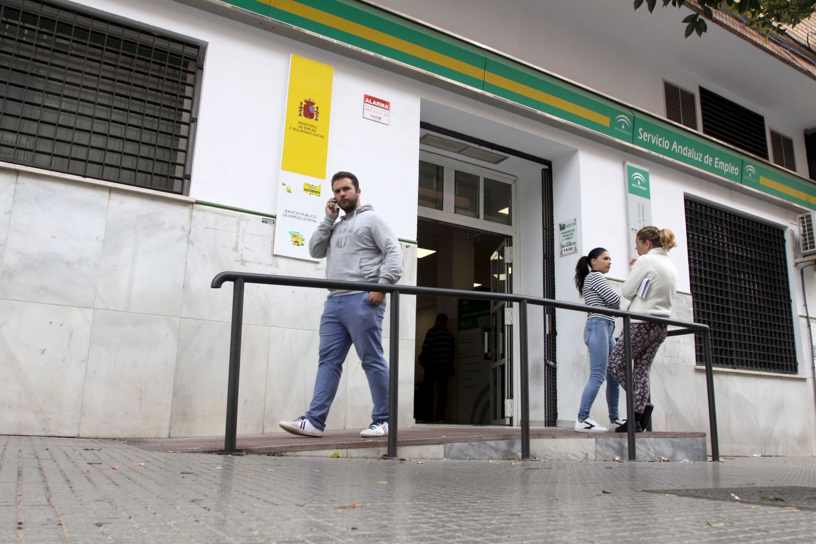 Varias personas esperan a las puertas de las oficinas del paro.