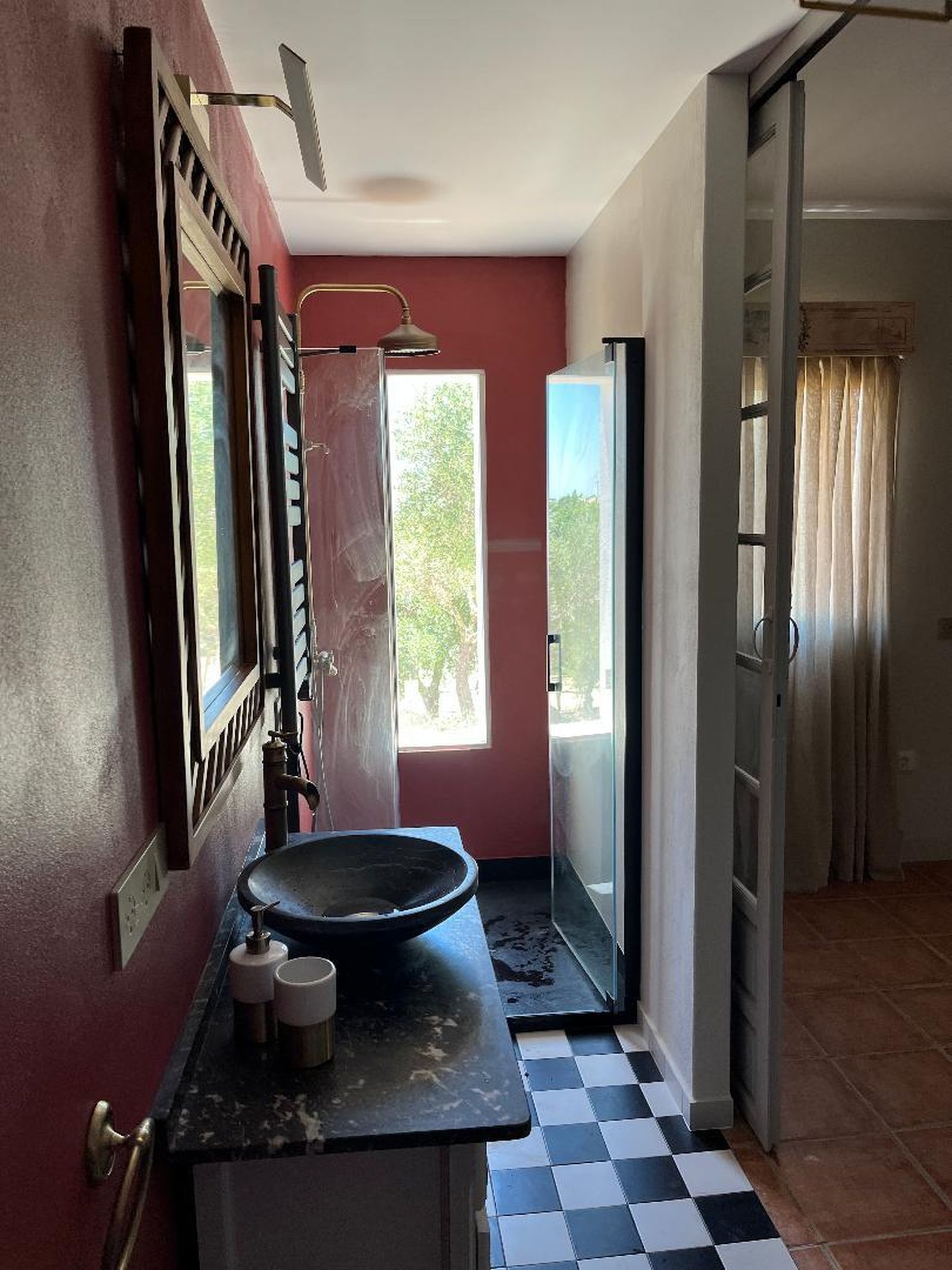 El baño combina el rojo de la pared con el damero en blanco y negro del suelo.