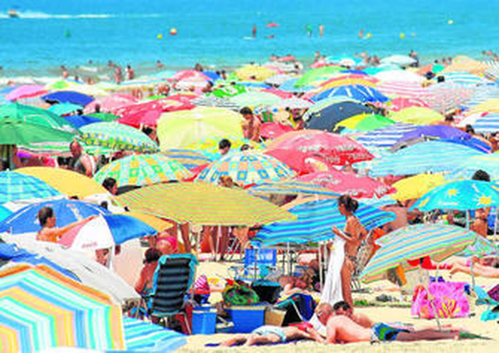 La orilla de la playa de Matalascañas abarrotada de sombrillas y bañistas.