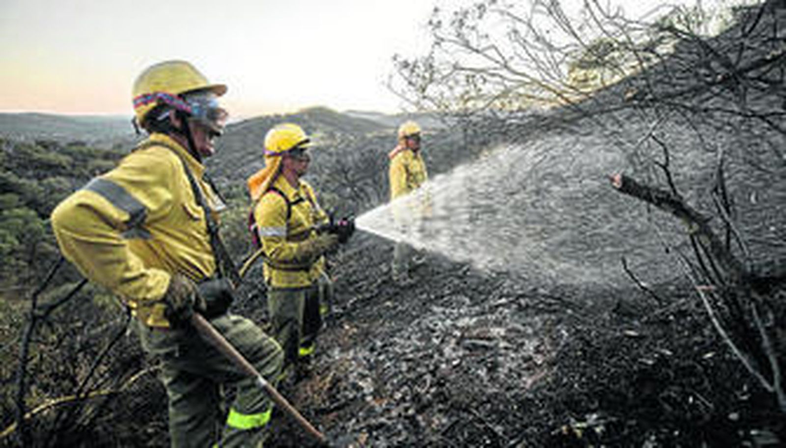 Unos bomberos del Infoca trabajan en la extinción del fuego de El Ronquillo, la tarde del domingo.