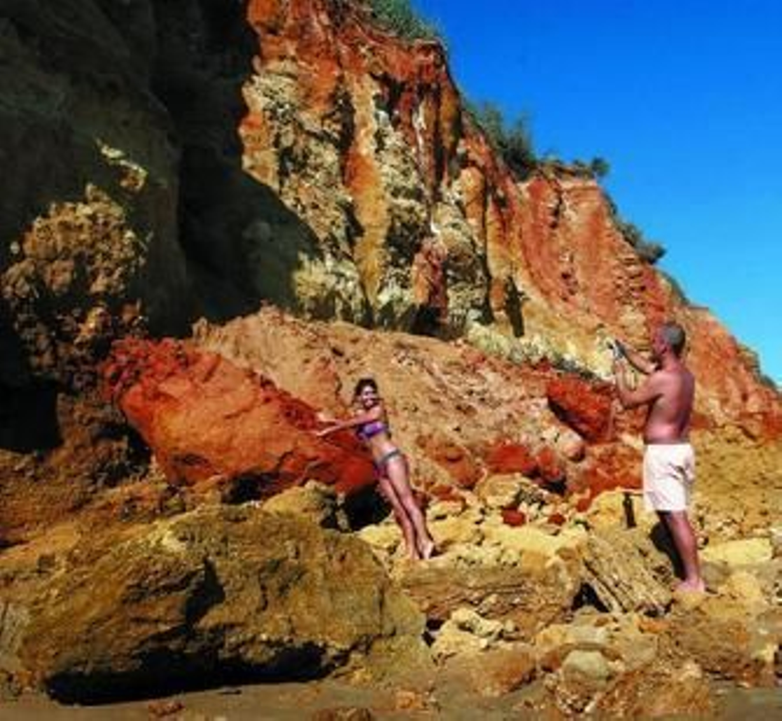 Una bañista posa para su pareja junto a una de las grandes rocas que cayeron del acantilado.