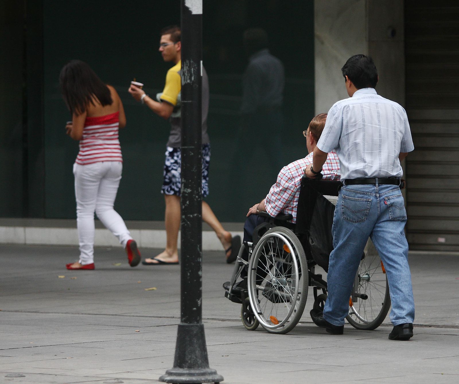 Una persona ayuda a otra en silla de ruedas.