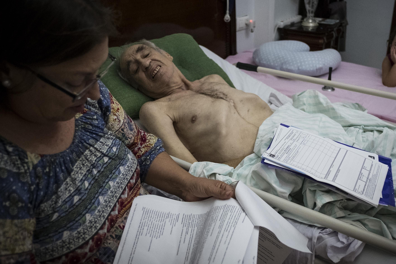 Rosario Muñoz, al pie de la cama de su marido, postrado después de once operaciones y la amputación de una pierna.