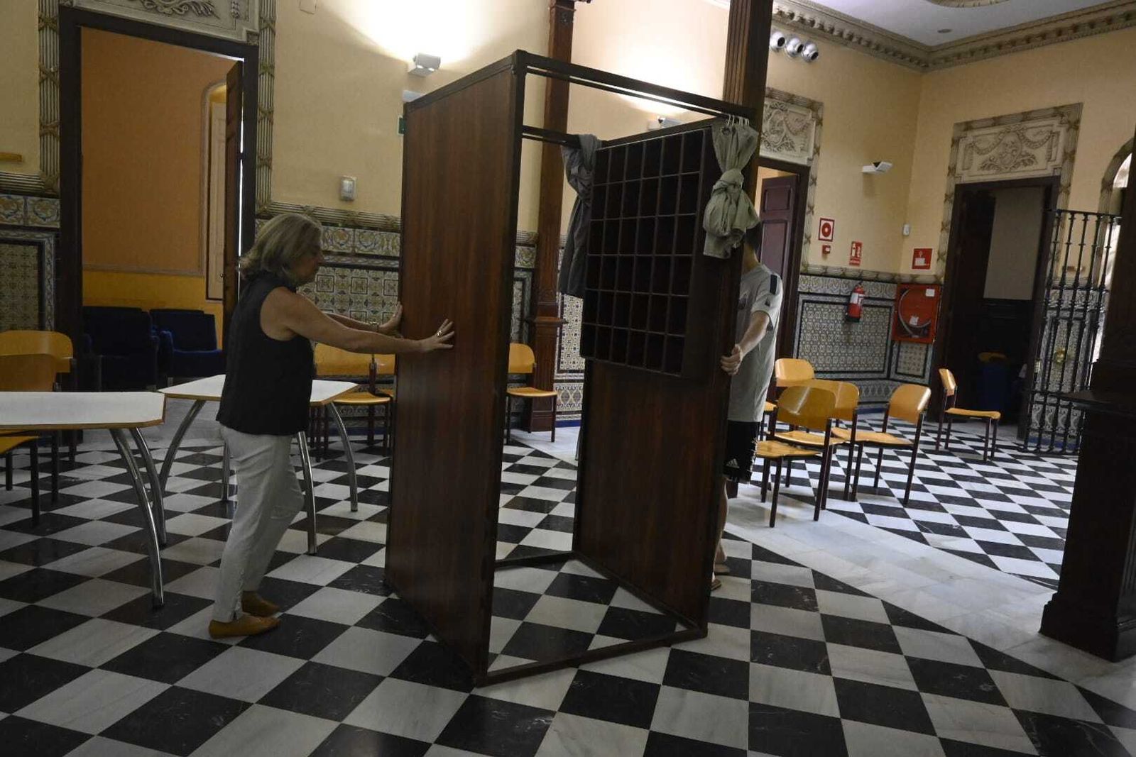 Dos personas mueven una cabina hasta un lugar más fresco en el colegio electoral de Mora Claros