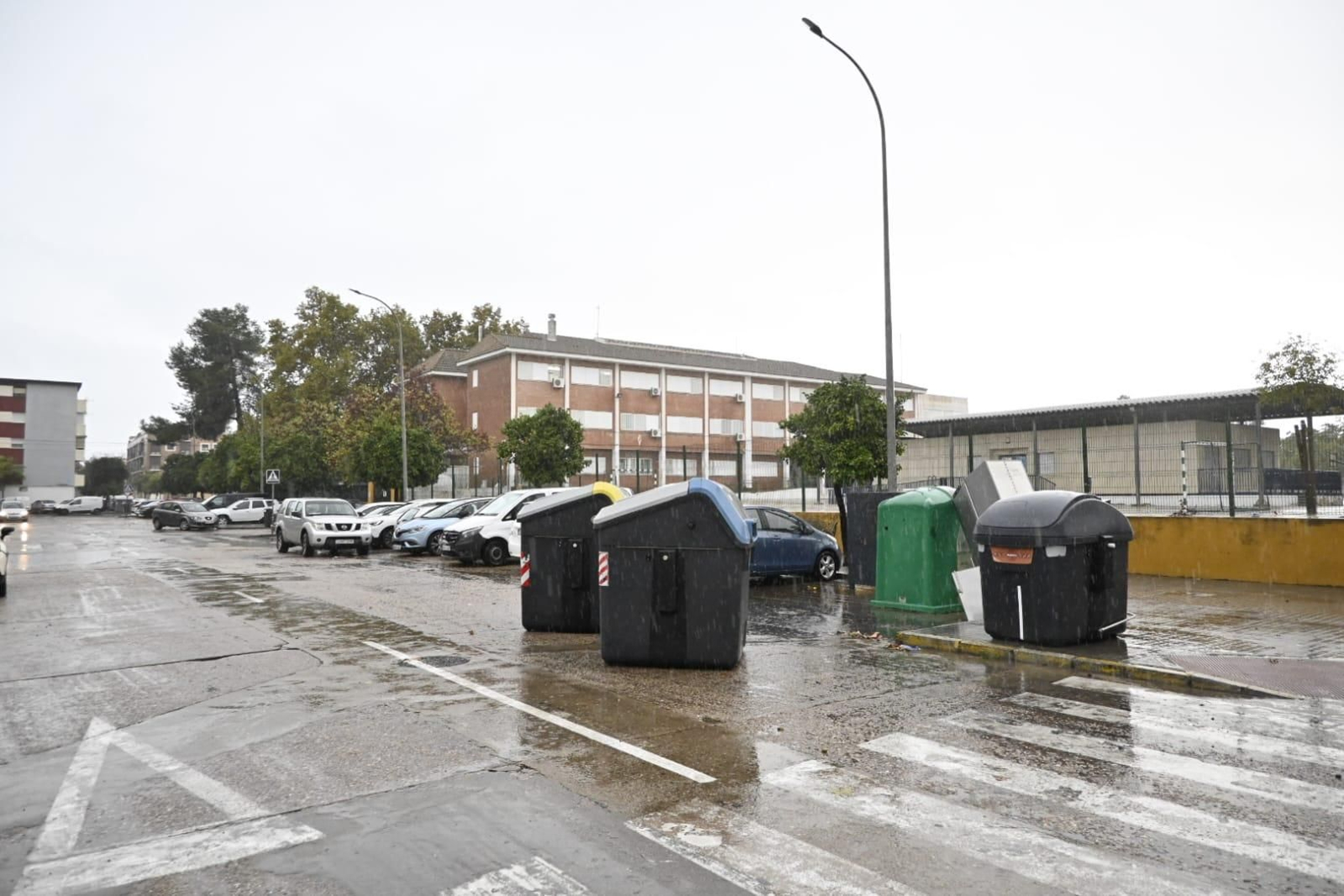 Contenedores desplazados por el viento junto al colegio de la barriada del Molino de la Vega en Huelva.