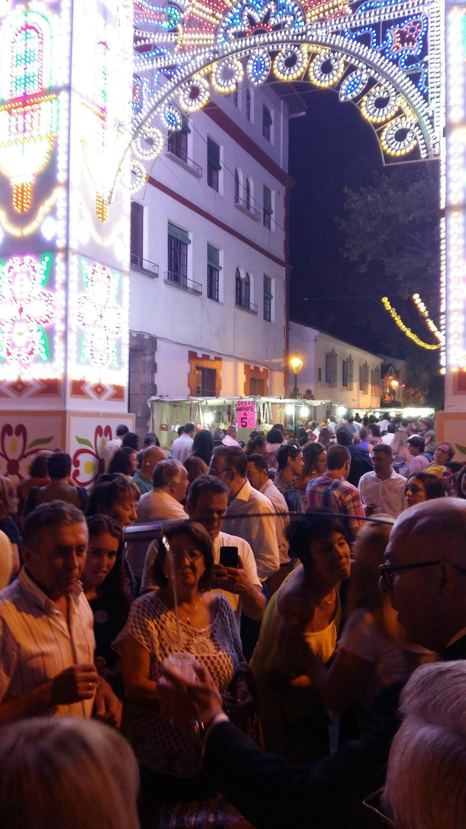 Un venenciador ofrece vino a la multitud ante la portada de la Feria aracenense.