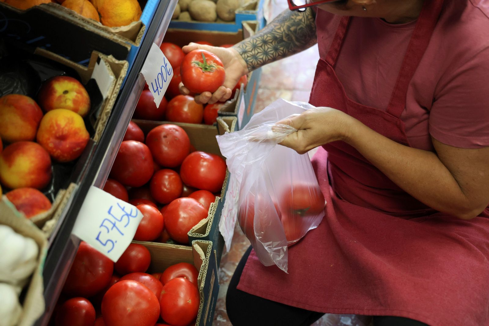 Trabajadora de Frutas y Verduras Ángel preparando una bolsa de tomates.