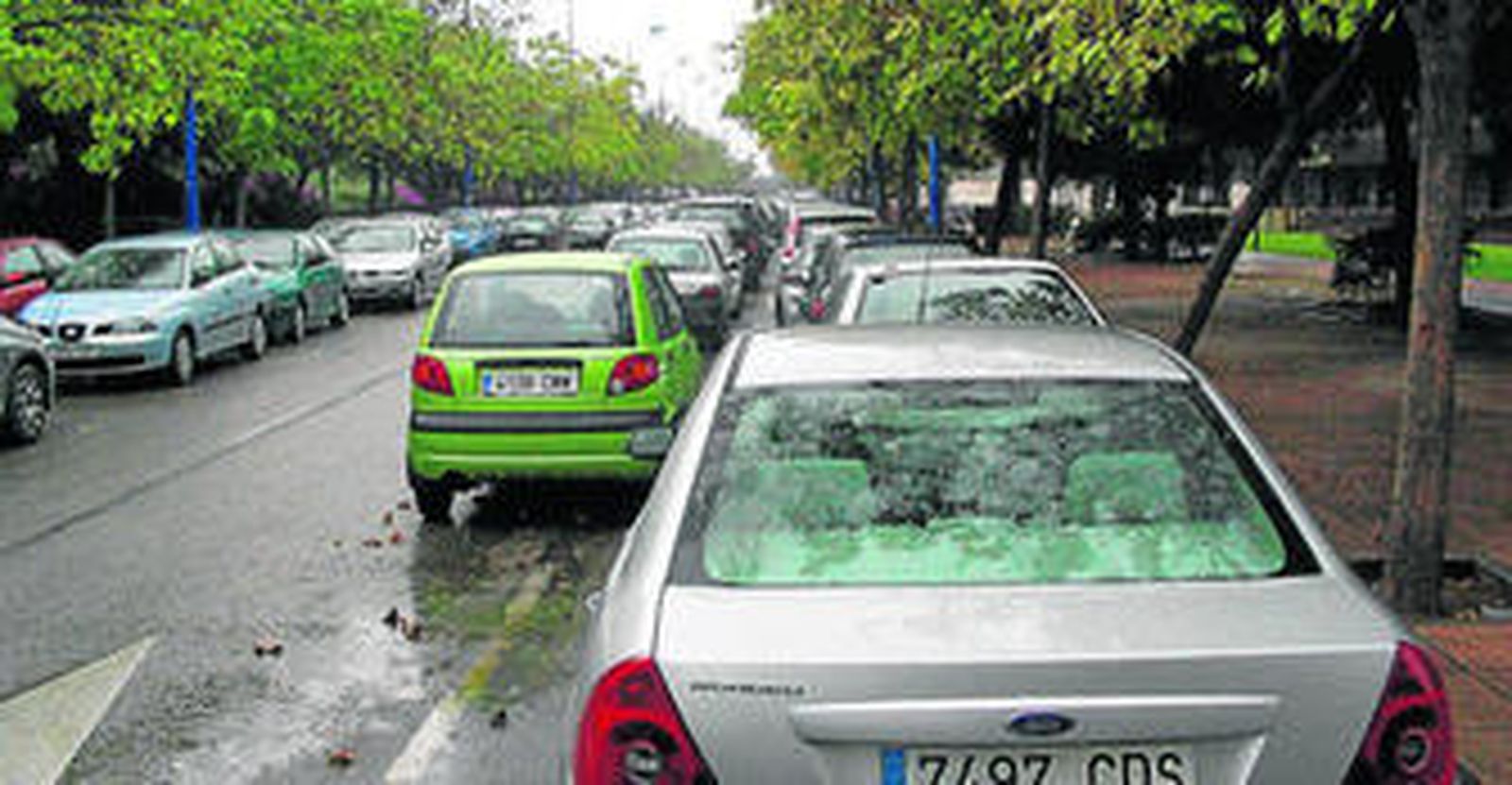 Vehículos aparcados en doble fila en las calles de la Isla de la Cartuja.