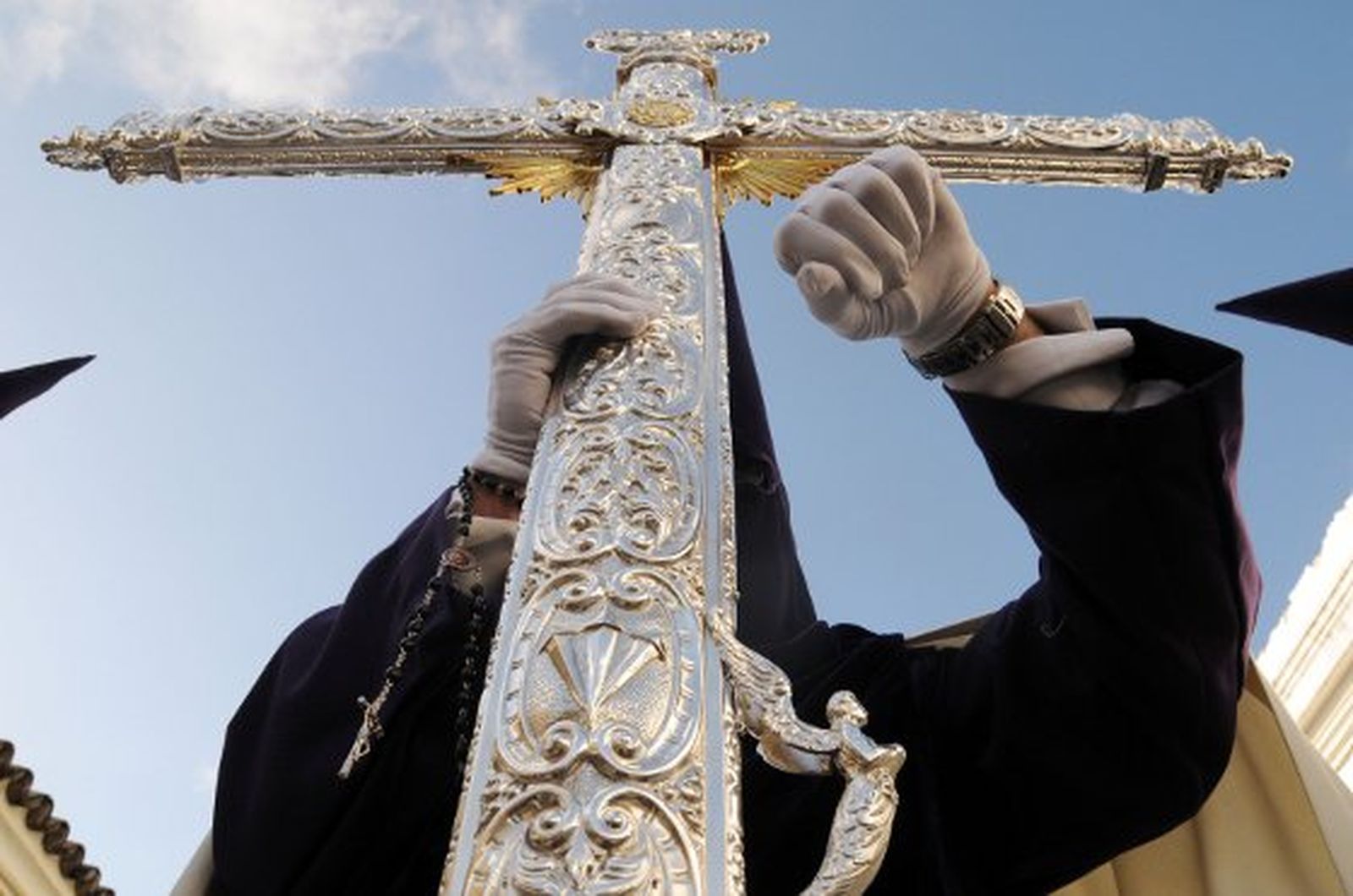 El nazareno que porta la Cruz de Guía mira la hora minutos después de salir de Santa Ana. La Candelaria fue la primera hermandad en decidir ponerse en la calle en la jornada del Lunes Santo.

Foto: Manuel Aranda