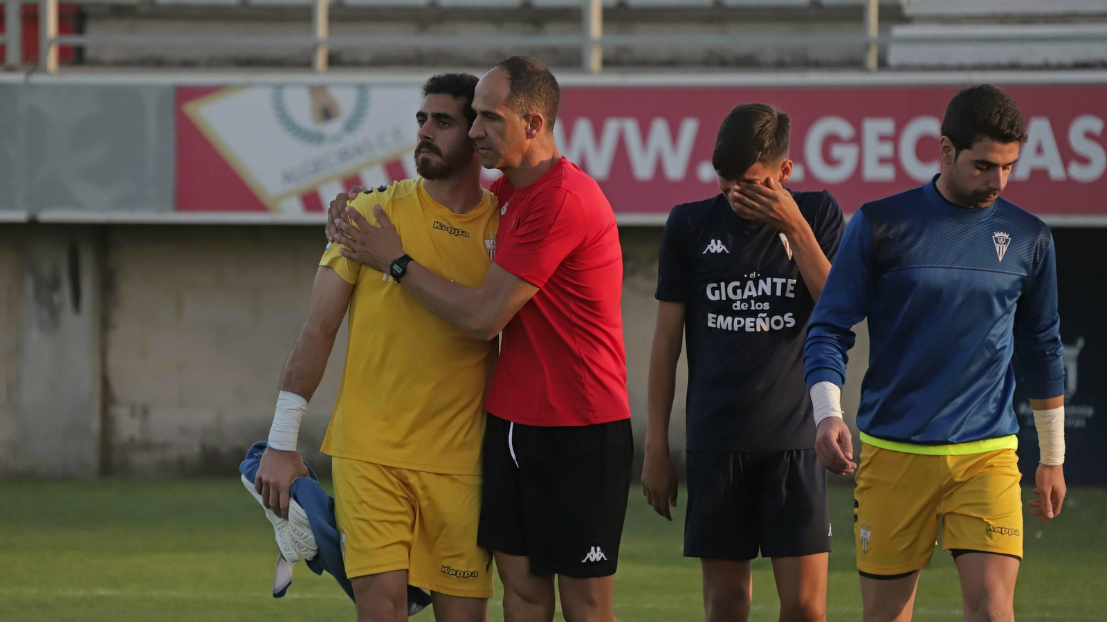 El meta del Algeciras Romero abandona el campo abatido y consolado por sus compañeros.
