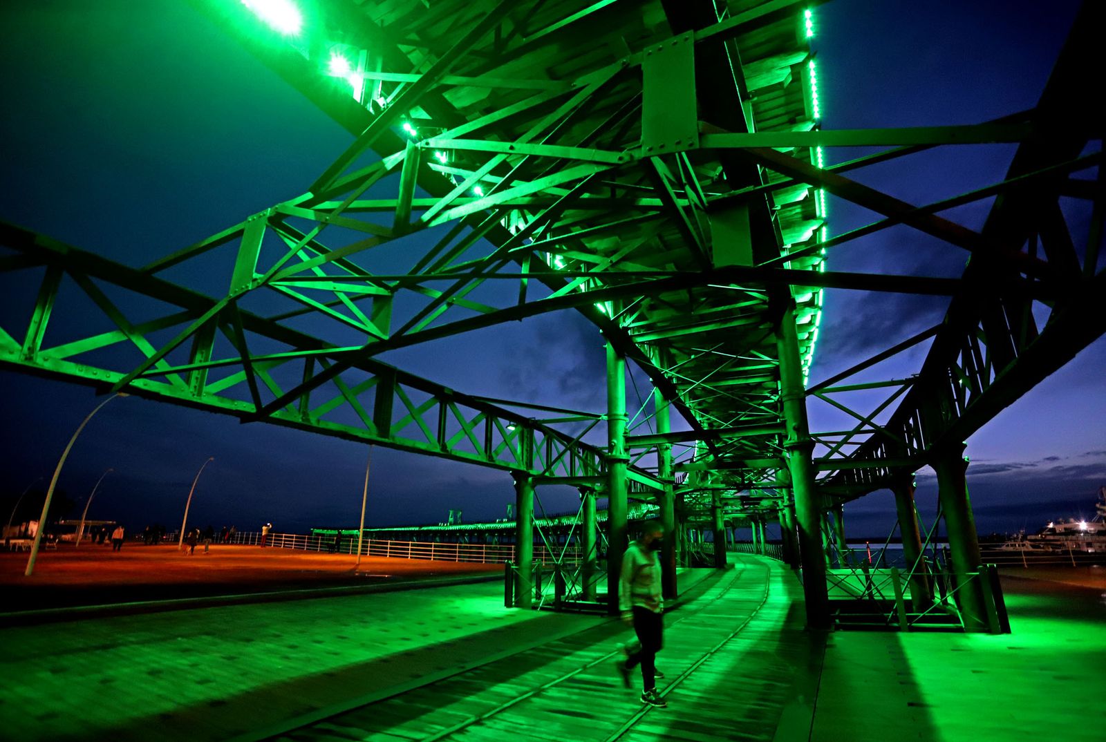 El muelle de la Riotinto se ilumina de verde en el día mundial contra el cancer