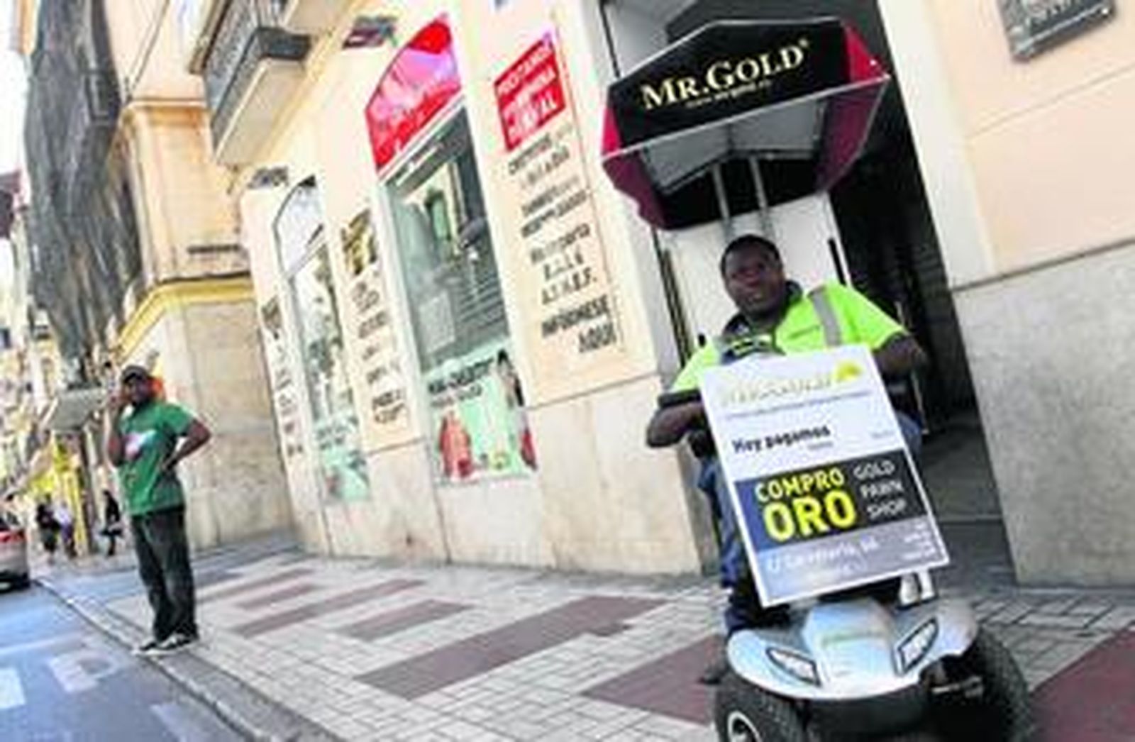 Un captador de clientes invita a los viandantes de la calle Carretería a entrar en su local de compraventa de oro.