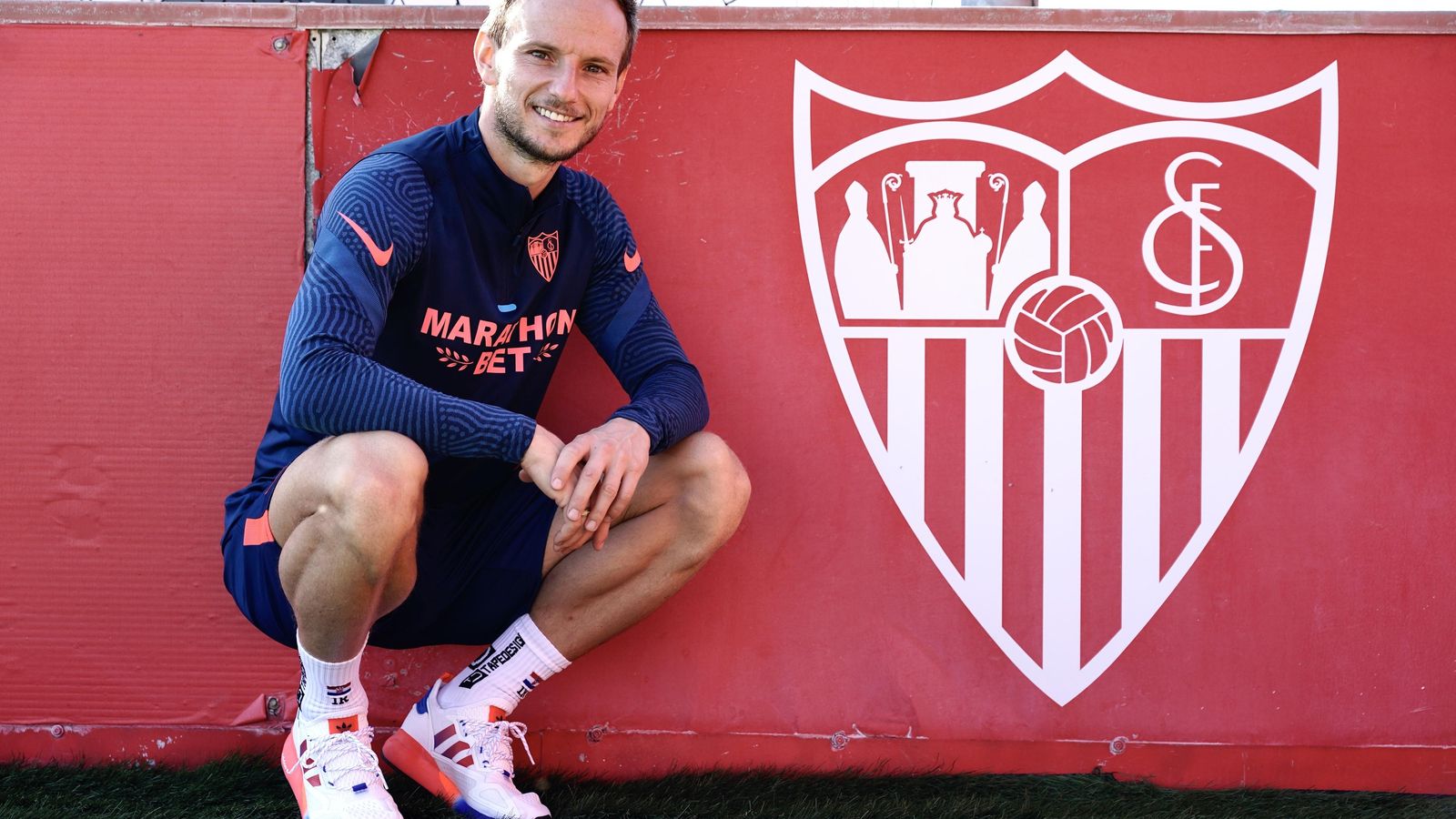 El croata posa junto a una valla con el escudo del Sevilla.