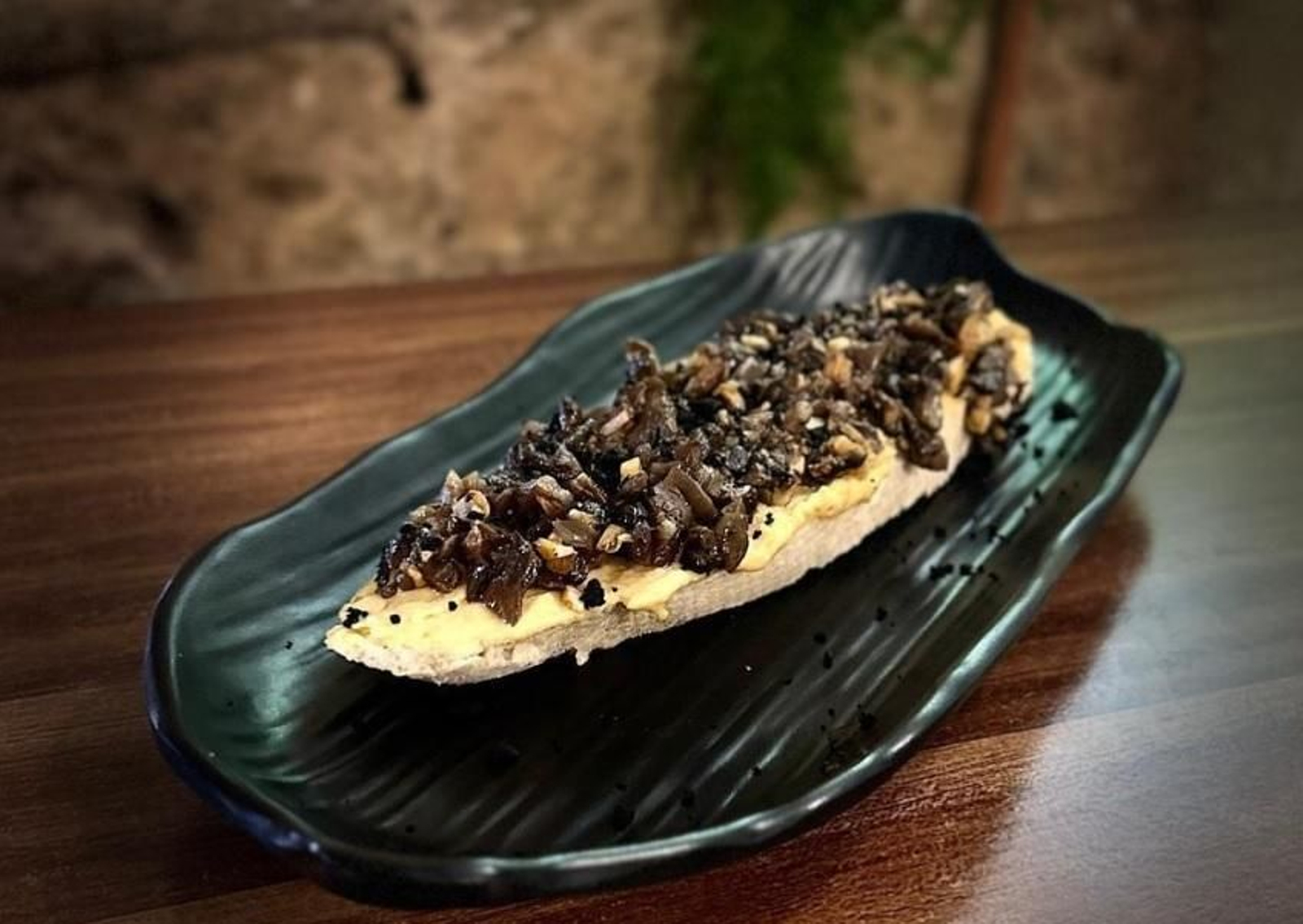 Plaza Colón Vinos y Tapas - Pincho de hummus con salteado de setas al ajillo y polvo de aceituna negra