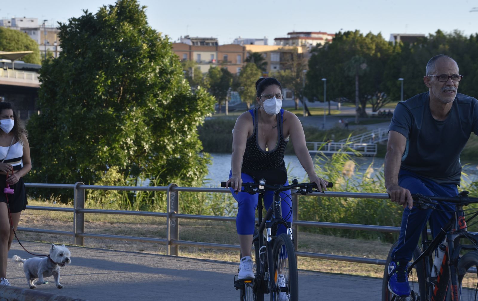 Varias personas pasean o hacen deporte por el paseo del río.