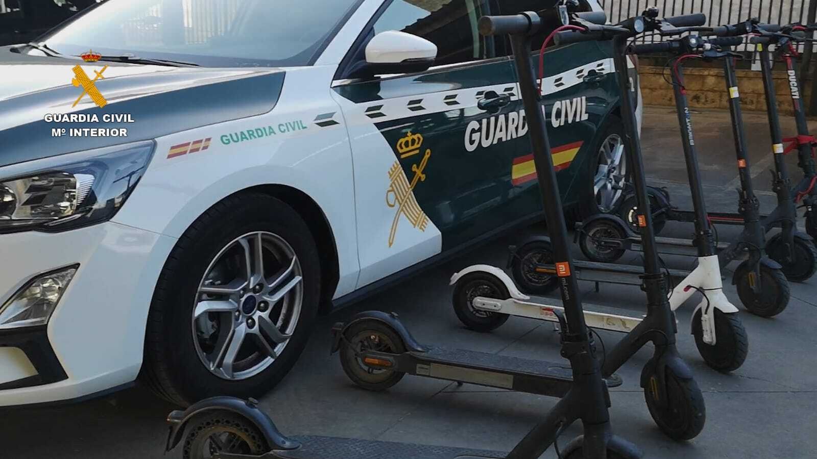 Un patrullero de la Guardia CIvil junto a los patinetes incautados en la operación.