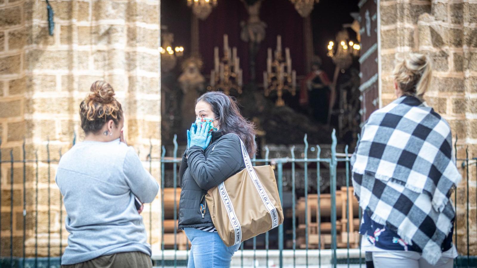 Varias personas se detienen en la puerta de la iglesia de La Palma, que ha abierto unos instantes este Lunes Santo