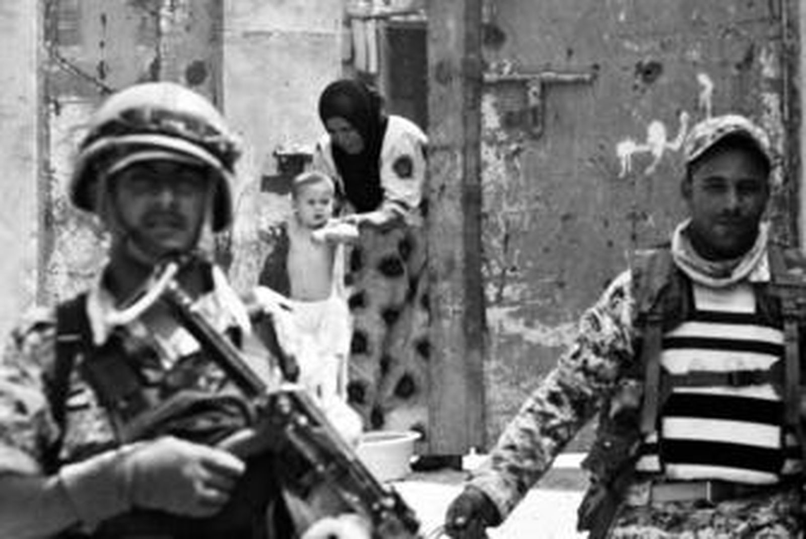 Una mujer baña a su hijo mientras soldados patrullan las calles de la ciudad de Amara, en Iraq.