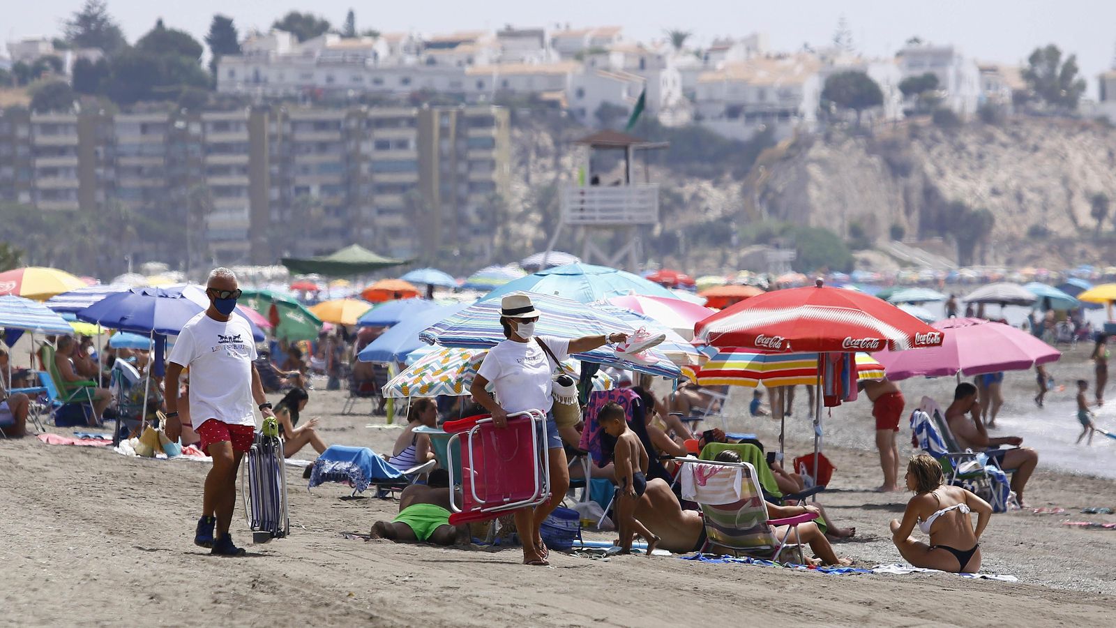 Dos hombres buscan hueco en una playa del Rincón de la Victoria.