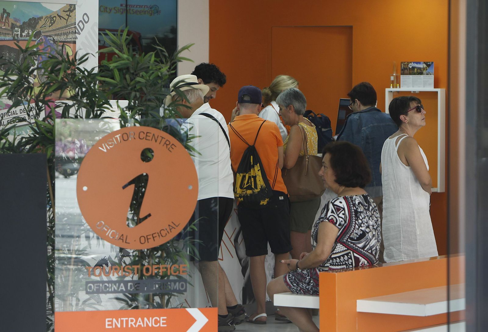 Los visitantes pidiendo información sobre Sevilla en una oficina de turismo.jpg