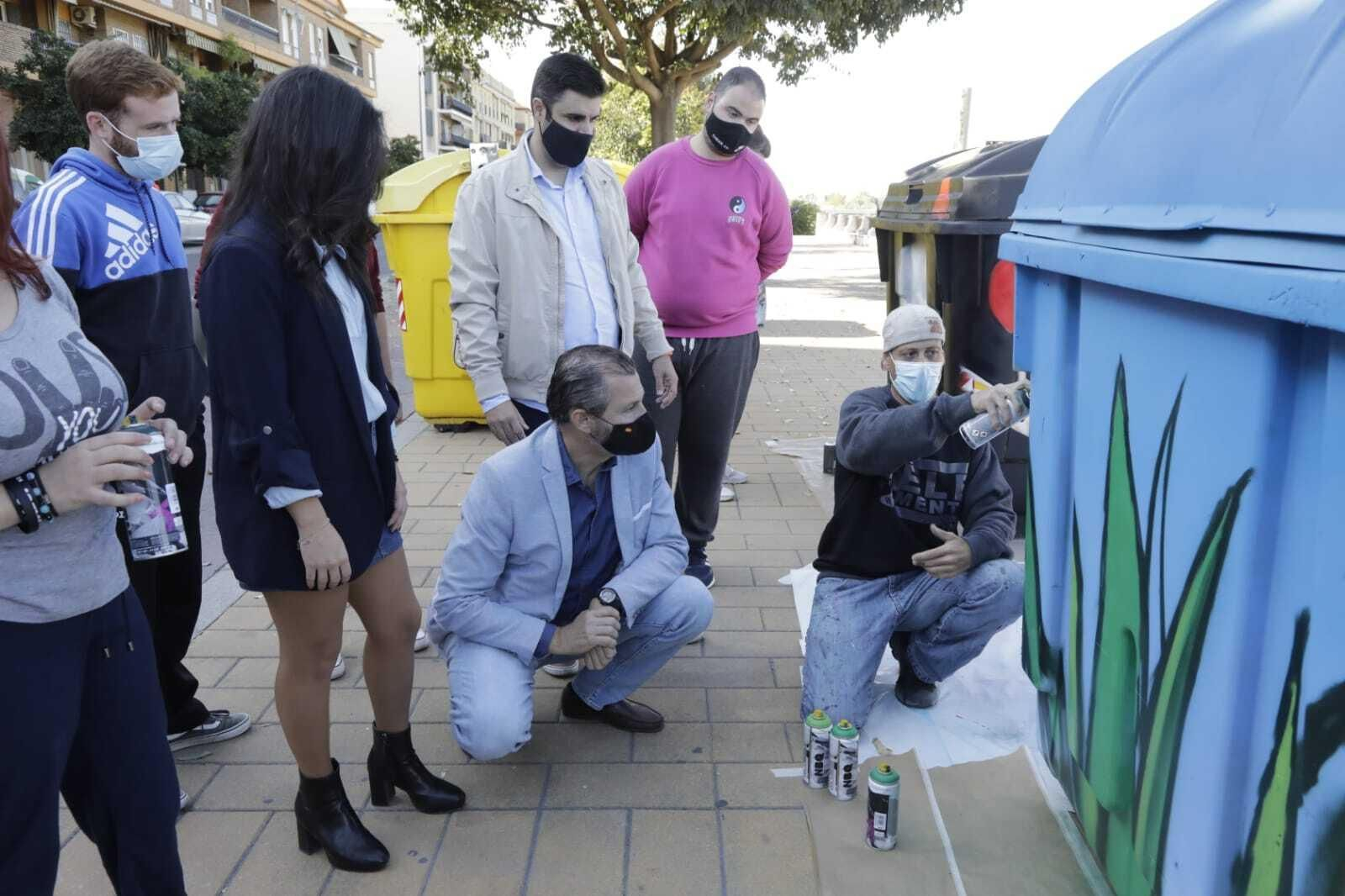 Cintia Bustos, David Dorado y Salvador García observan la realización de un grafiti en un contenedor.