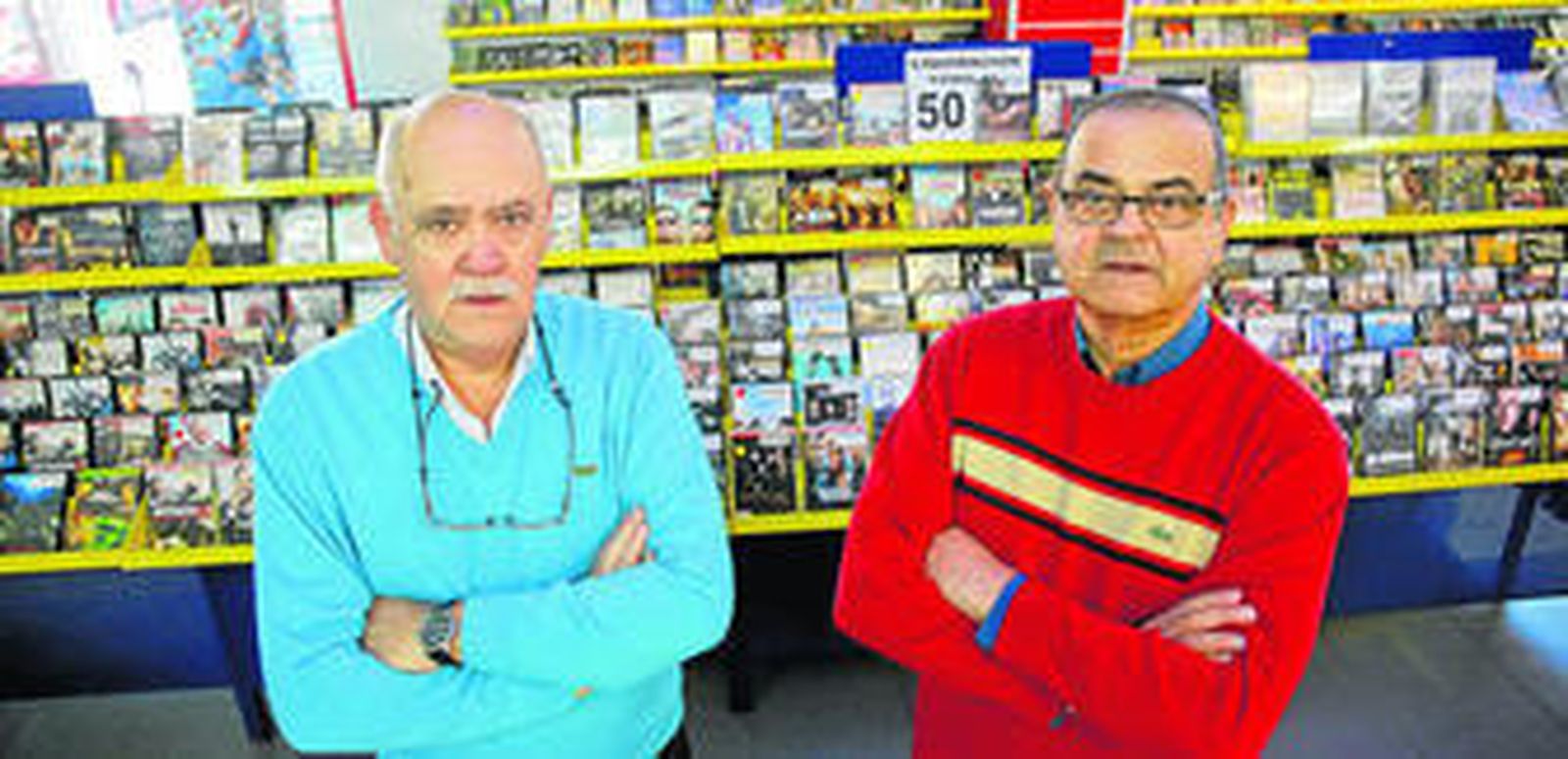 Rafael y Diego, dueños del videoclub El Torcal, posan junto a las películas, que han puesto a la venta con grandes descuentos.