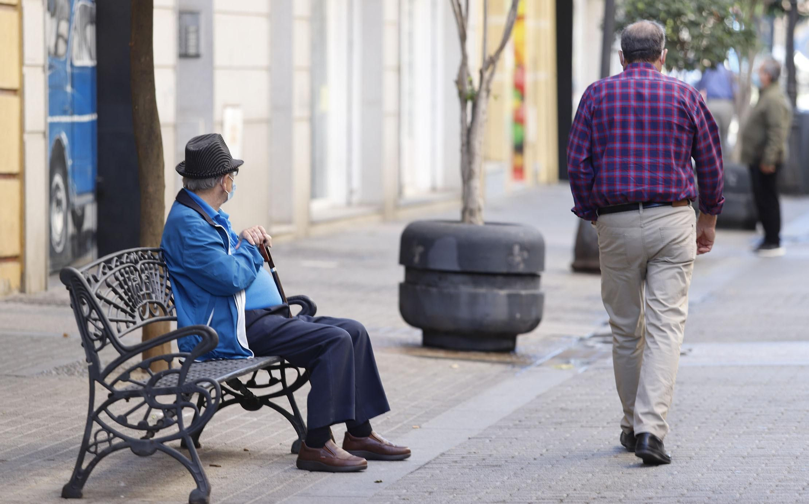 Un banco y un macetero, parte del mobiliario urbano actual en la céntrica calle Marina entre transeúntes.