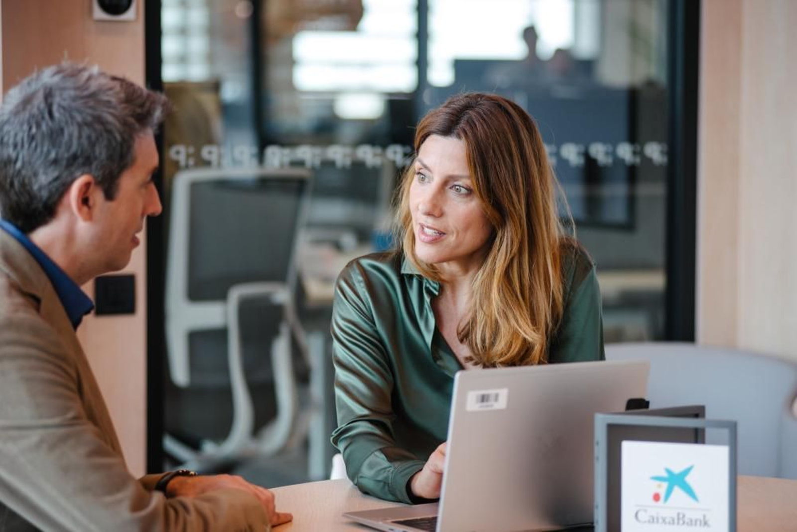 Una trabajadora de CaixaBank atiende a un cliente.
