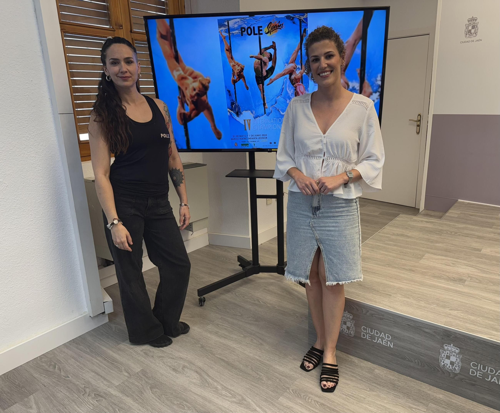 Beatriz López y Rouse de la Cruz posan con el cartel del evento.