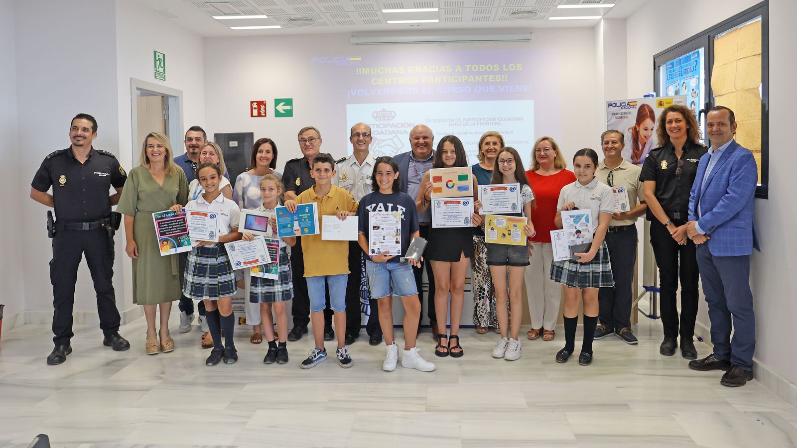 Alumnos premiados, profesores, padres y colaboradores posan en el Salón de Actos de la Policía Nacional con el comisario Francisco García y el responsable del certamen, Adrián Bezares.