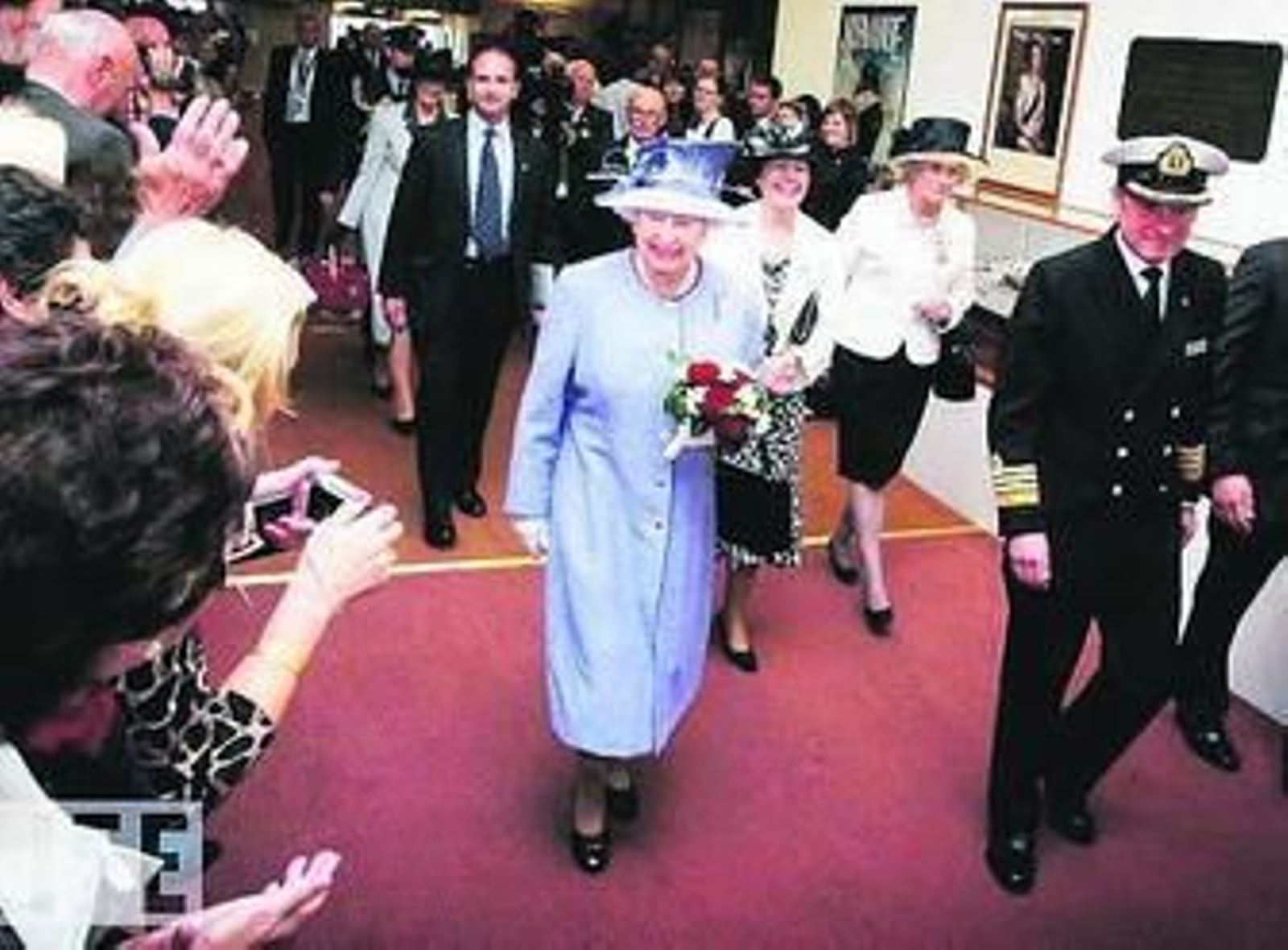 La reina de Inglaterra, acompañada del capitán Chris Wells, junto a quien visitó el trasatlántico tras su bautizo.