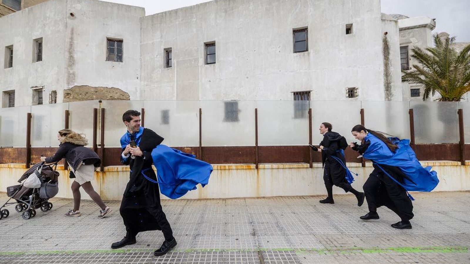 Penitentes de la cofradía de Las Aguas entre el fuerte viento en Cádiz este Miércoles Santo.