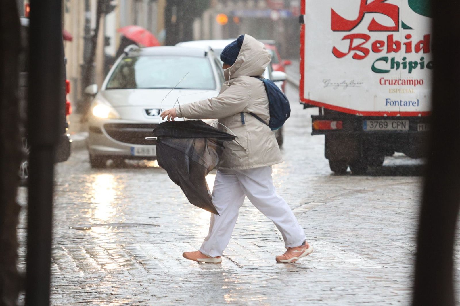 Una mujer con un aparaguas roto por el viento, esta mañana en el centro de Jerez.