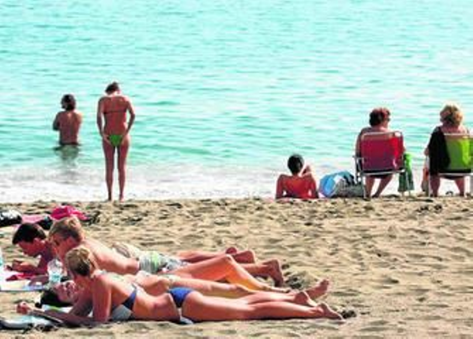 Un grupo de jóvenes toman el sol en una playa andaluza.