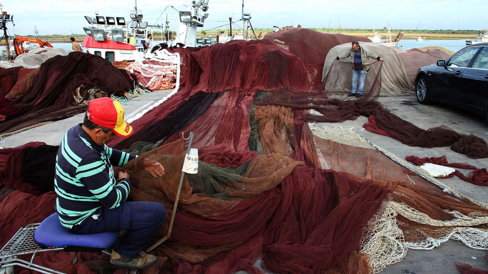 Dos marineros reparan las redes de pesca.