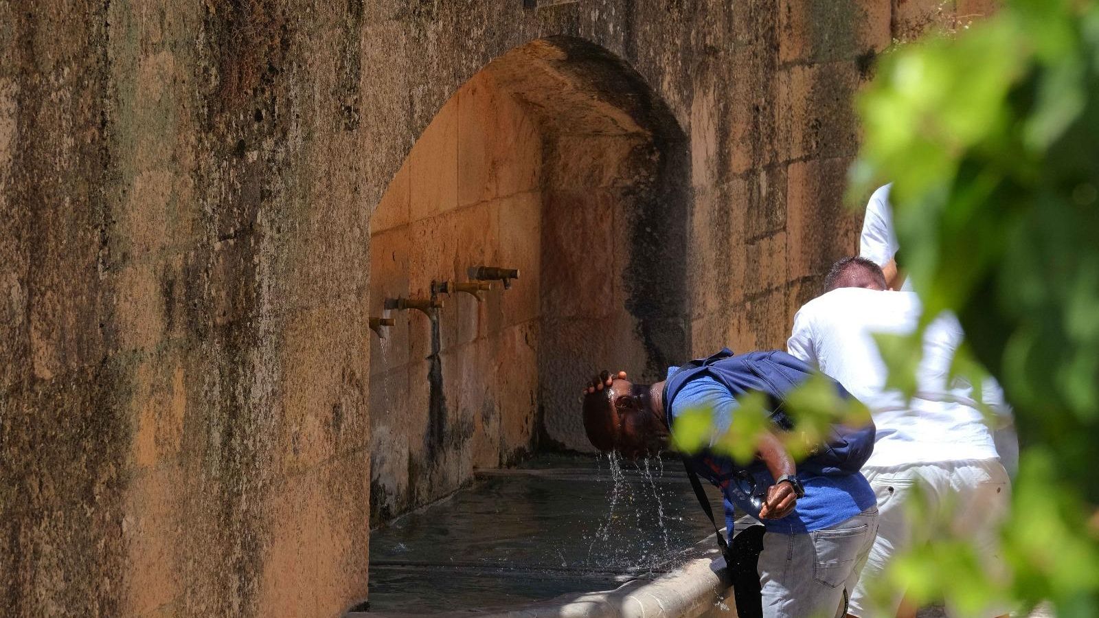 Varias personas se refrescan en una fuente en Ronda.
