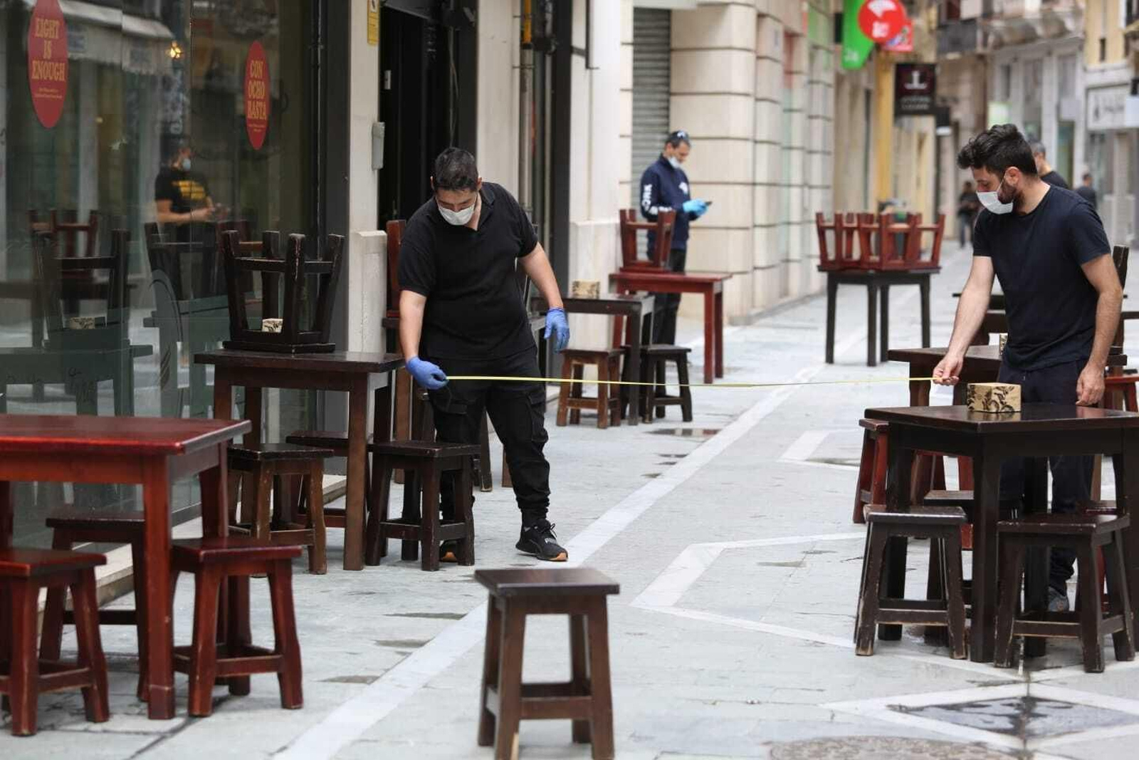 Trabajadores de un bar de Málaga miden la distancia entre las mesas.