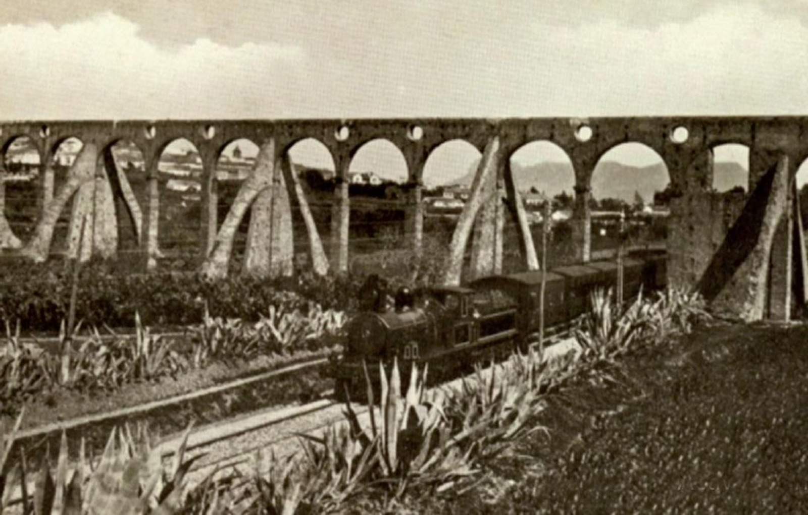 El acueducto en el año 1904. En primer término un tren tirado por una máquina tipo “American” saliendo de la estación de Algeciras.