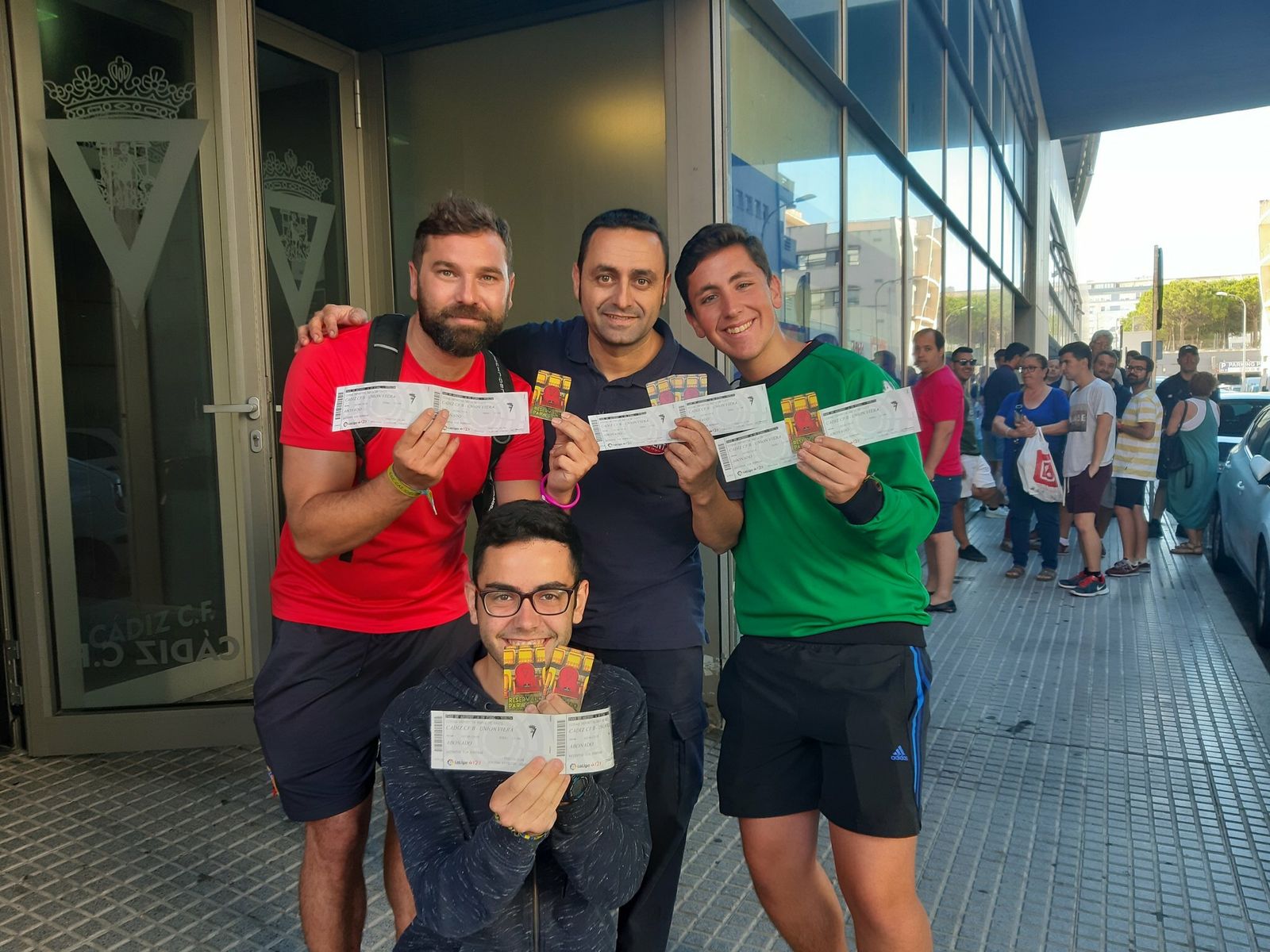 Unos aficionados muestran sus entradas mientras otros guardan cola.