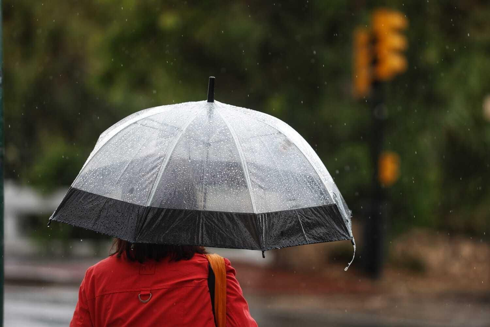 Una mujer protegiéndose de la lluvia en Málaga.