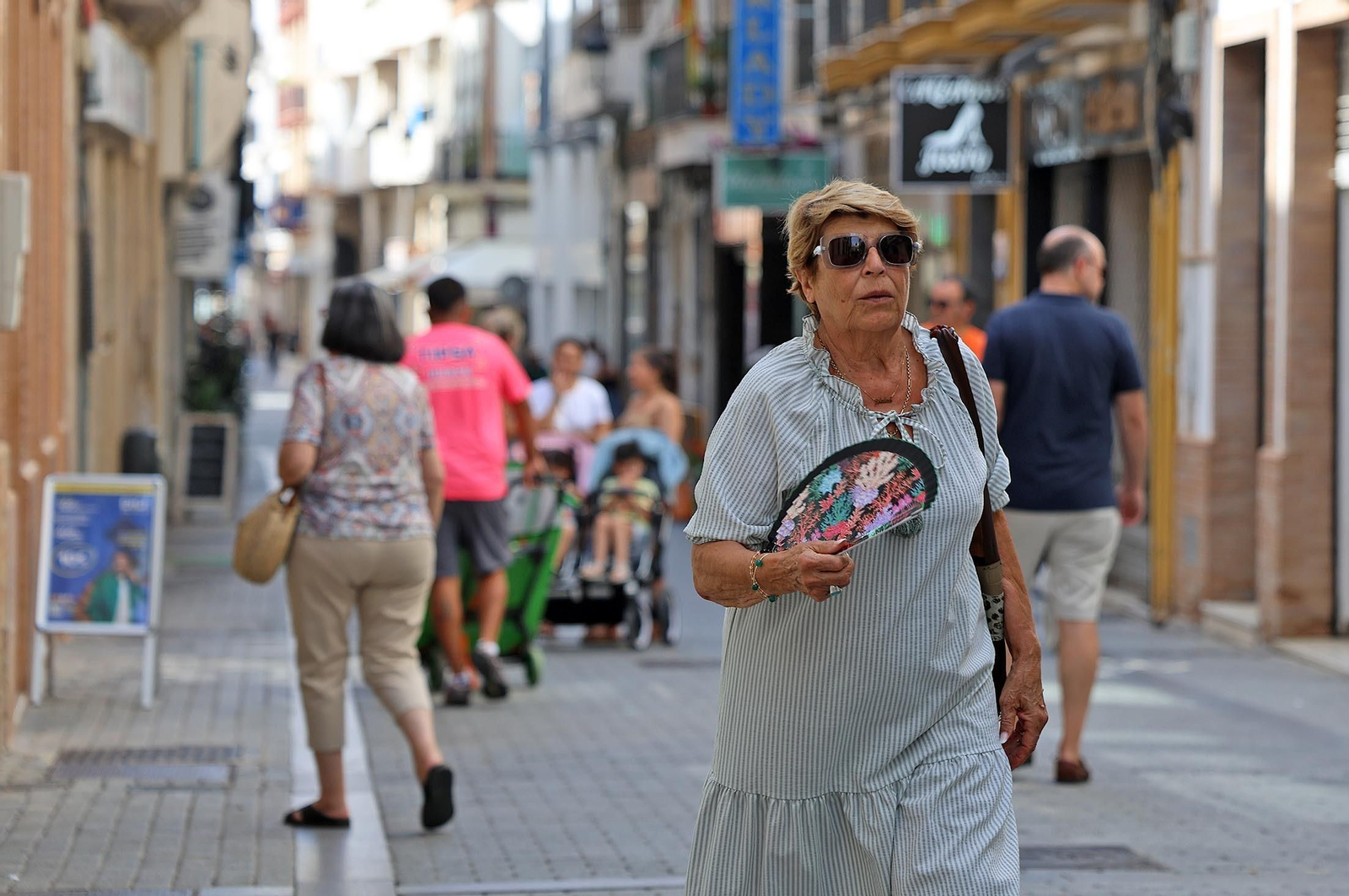 Una señora se abanica para refrescarse durante un paseo en la calle.