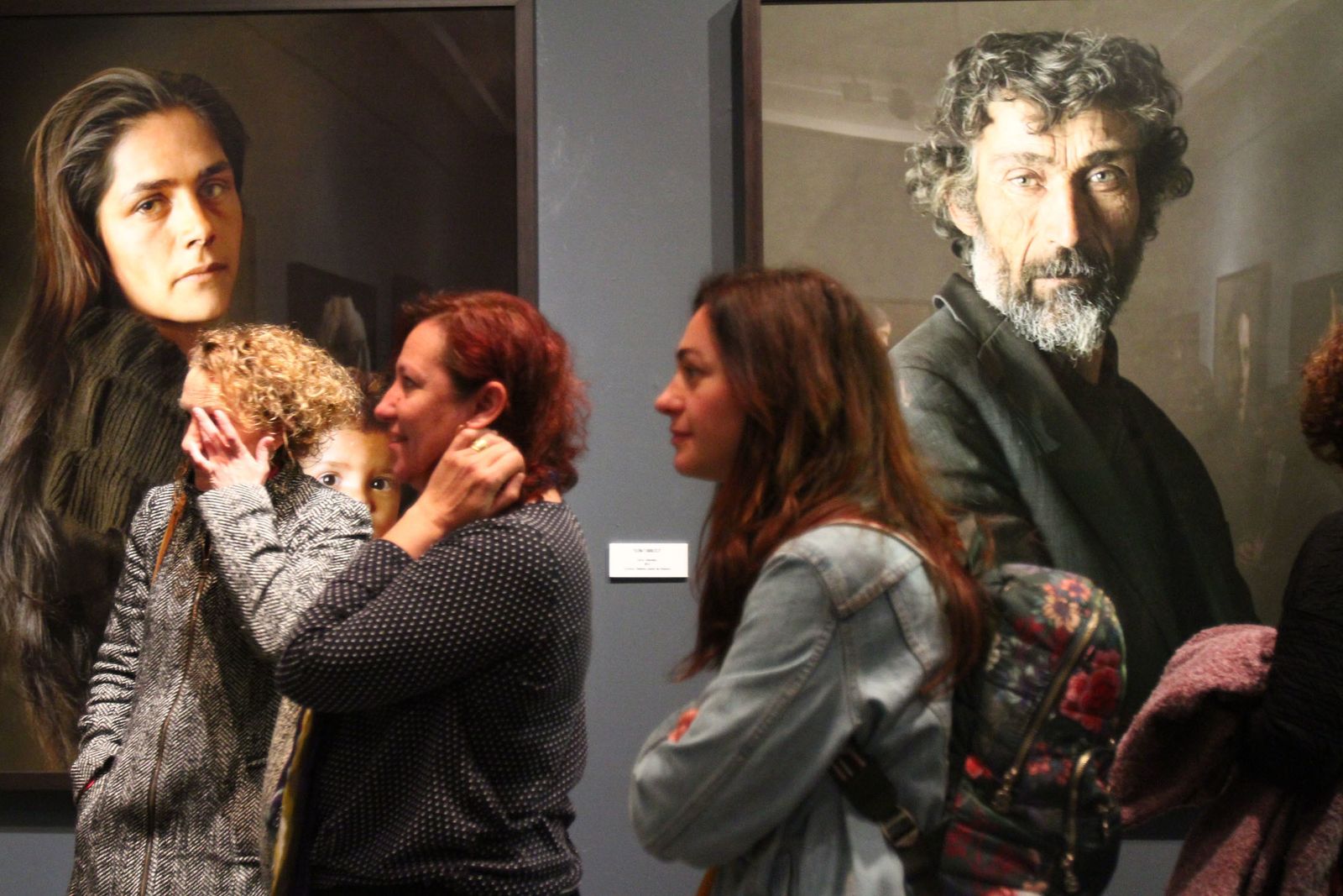Tres mujeres pasan por dos retratos de Pierre Gonnord.