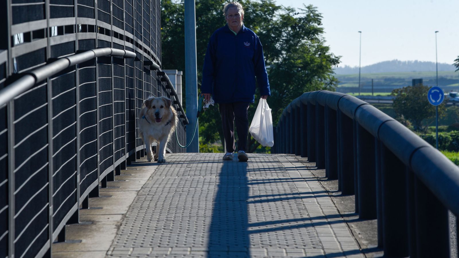 Una señora cruza una de las pasarelas de acceso al barrio.