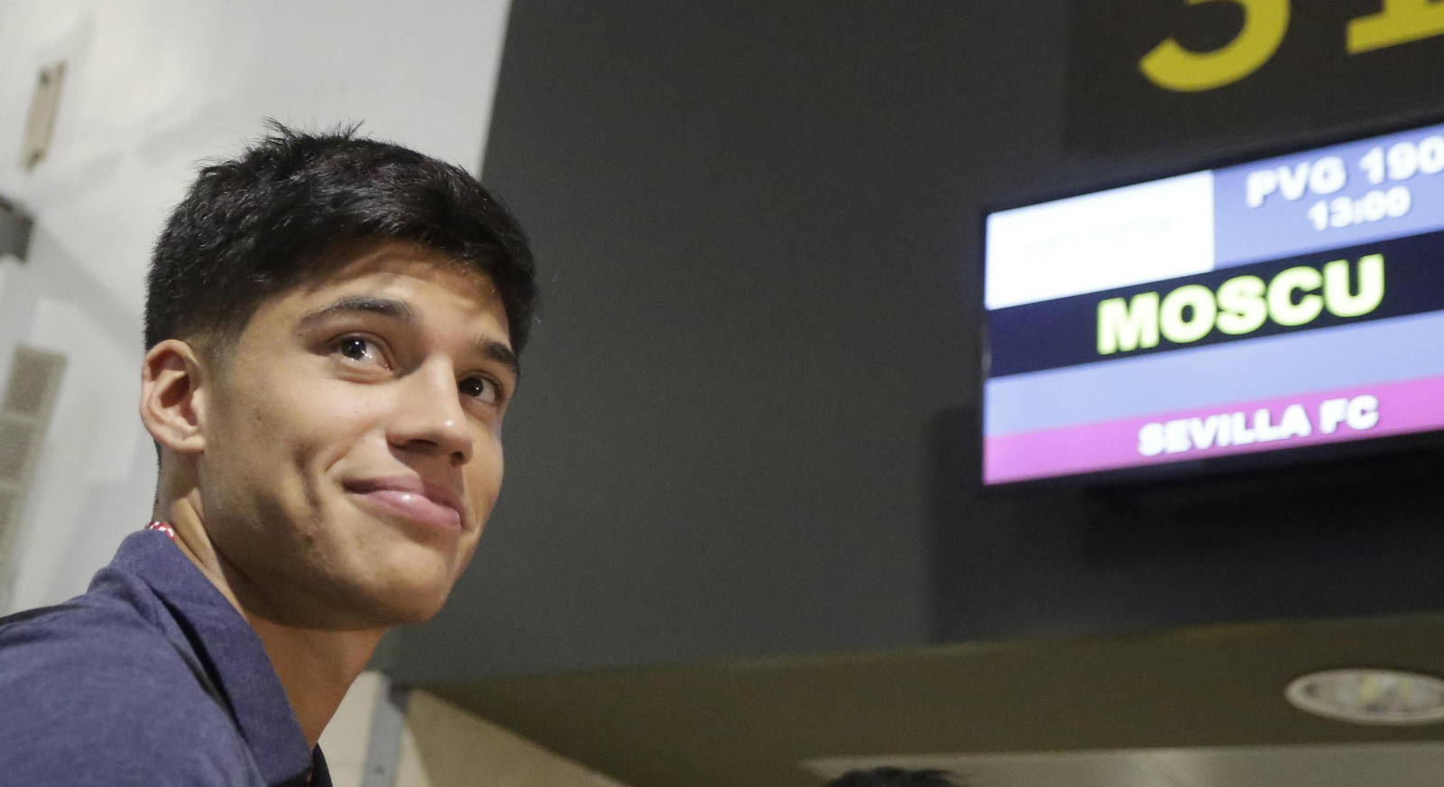 Correa sonríe ante un panel informativo que señala el destino del vuelo que tomó el Sevilla a mediodía de ayer.