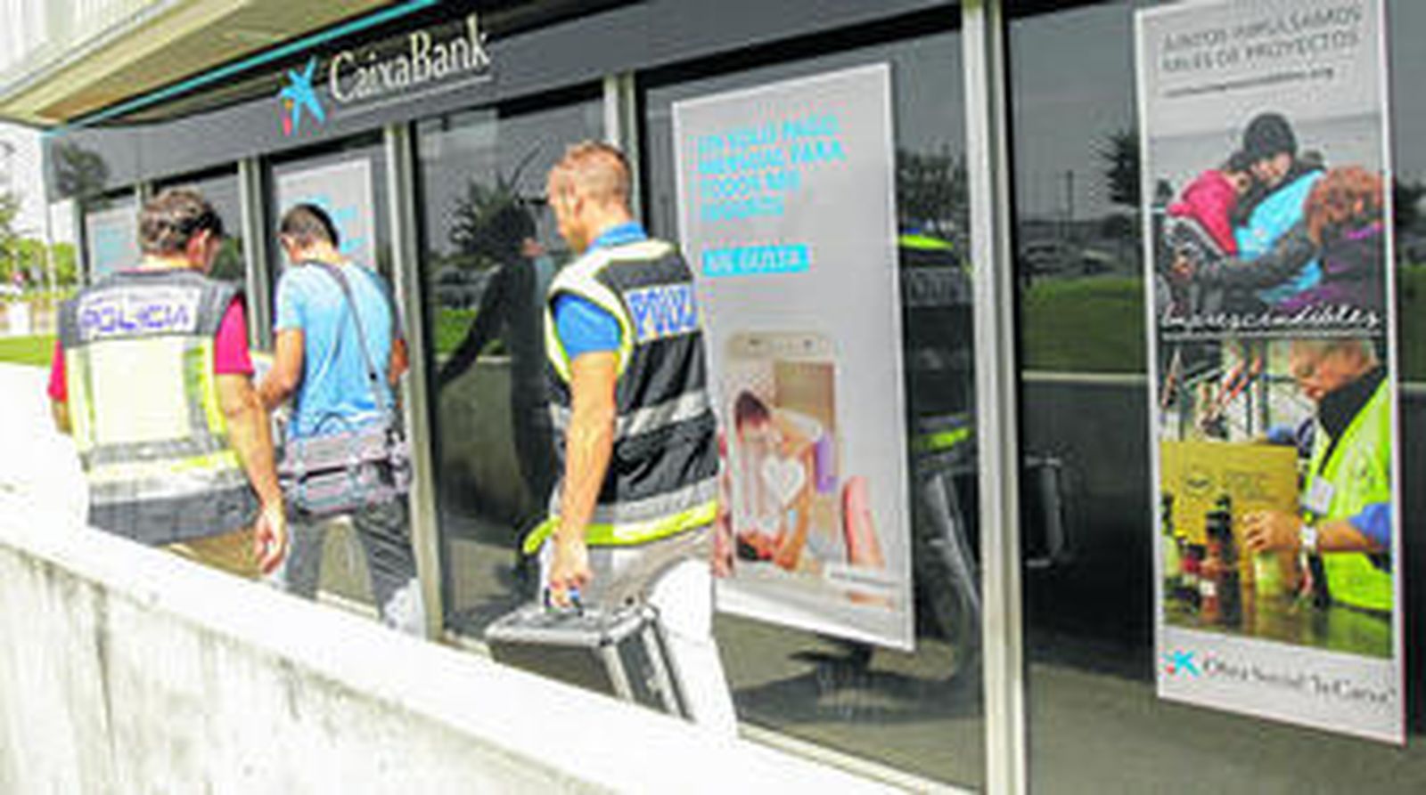Miembros del Cuerpo Nacional de Policía se marchan de la sucursal tras analizar el lugar para obtener pruebas de lo ocurrido.