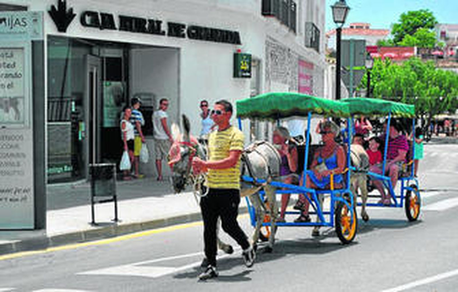 Un arriero transporta a unos turistas en un burro-taxi por Mijas.