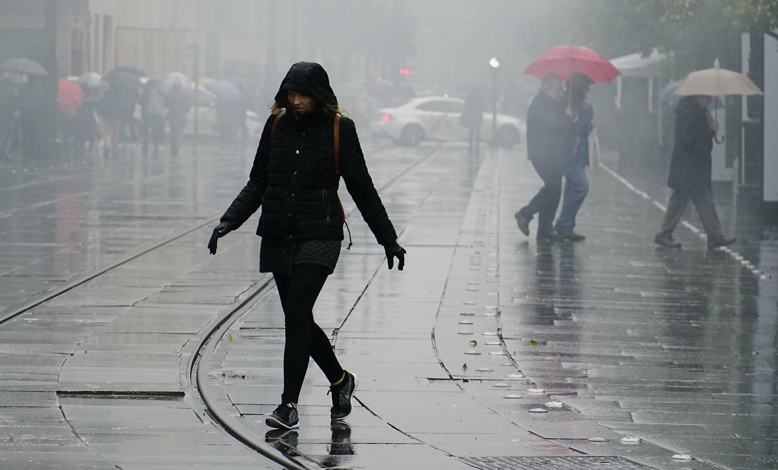 Una joven cruza la Avenida de la Constitución un día de lluvia y niebla en Sevila.