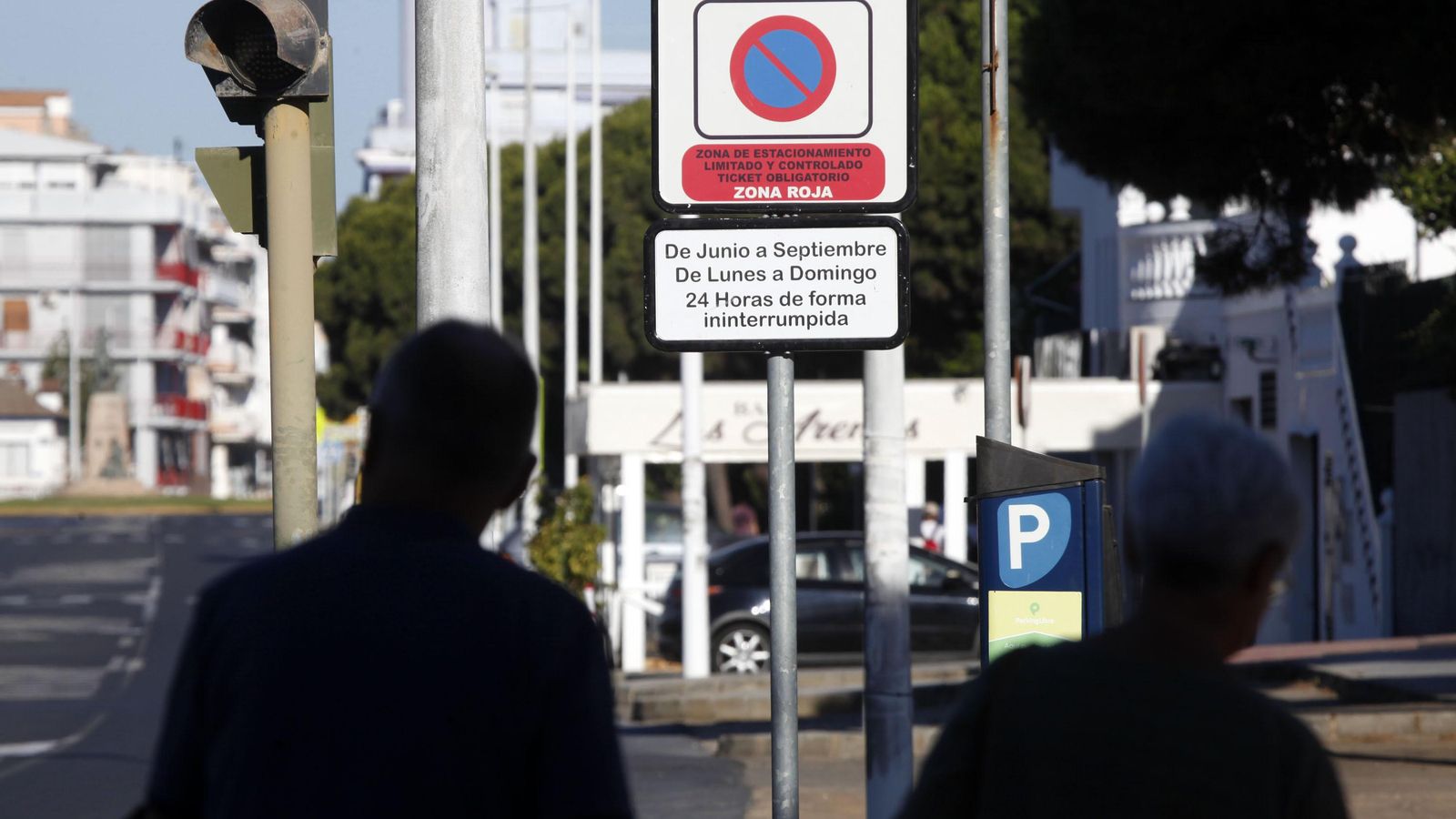 Dos personas consultan la información sobre la zona regulada de pago en Punta Umbría