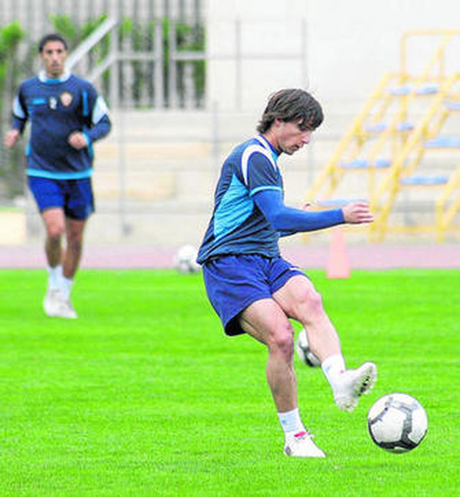 Piatti golpea un balón en el entrenamiento, con Pellerano corriendo en segundo plano.